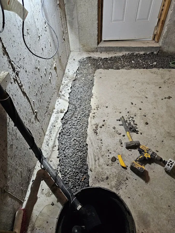 Clean basement area with newly installed black drain pipe and red fire extinguisher after restoration work