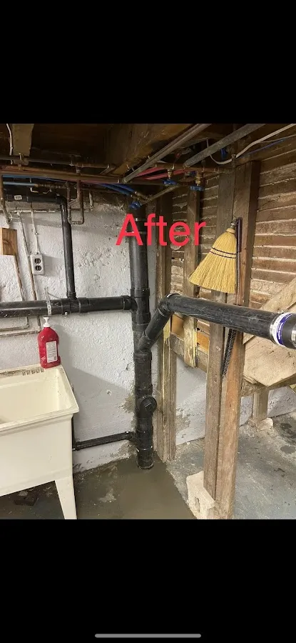 Outdoor trench showing black drainage pipe installation in excavated area adjacent to building foundation