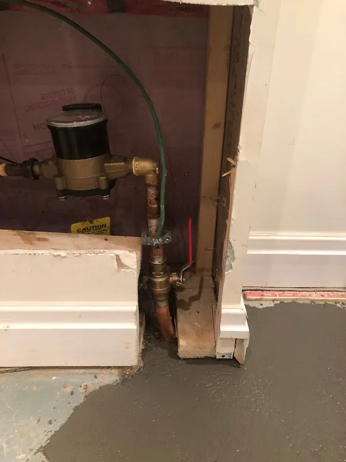 Sump pump installation in basement floor with collection basin and electrical connections setup