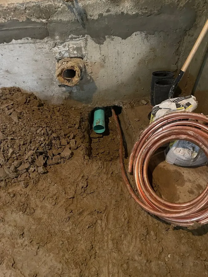 Outdoor green drainage pipe laid in yard trench with vegetation and landscaping visible