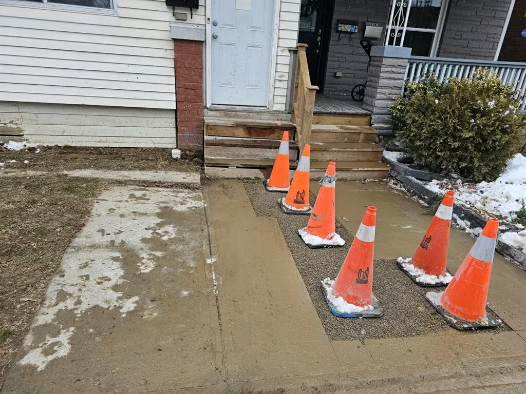Emergency response equipment including traffic cones and warning lights set on driveway for drain work