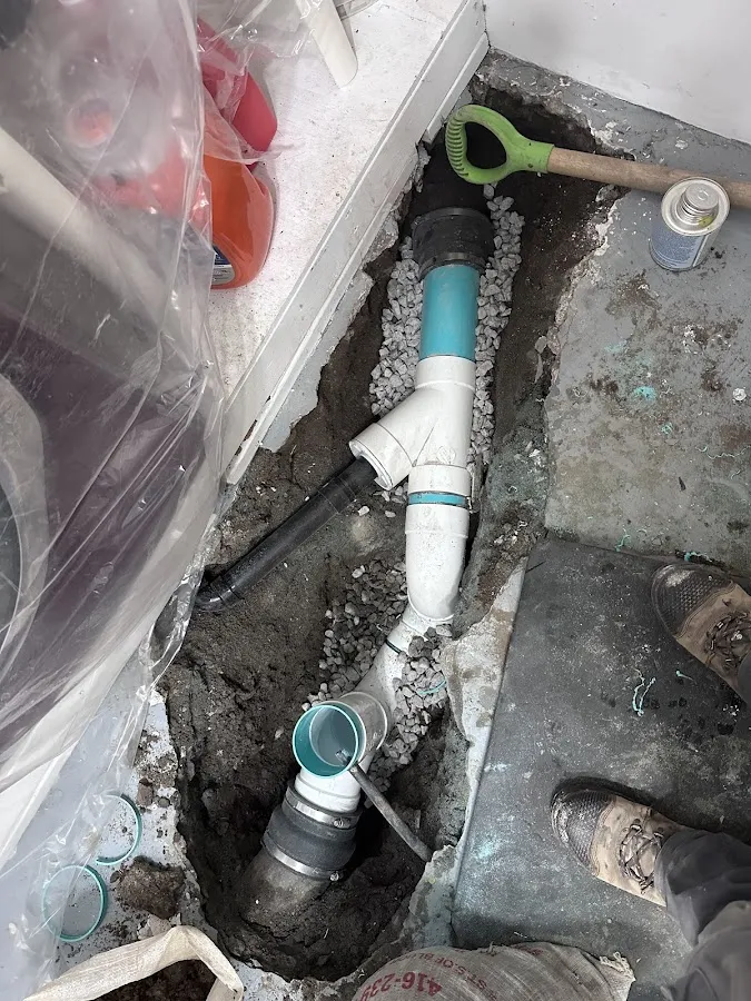 Foundation sump pump system with blue and white PVC drain pipes and connector fittings in basement