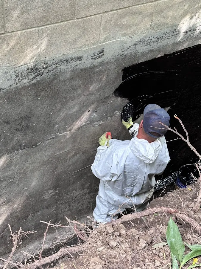 Technician inspecting sump pit area in confined basement space